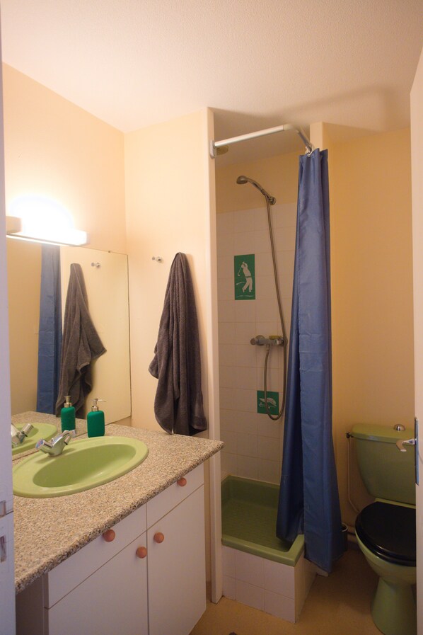 A bathroom with a green sink, a shower, and a toilet.