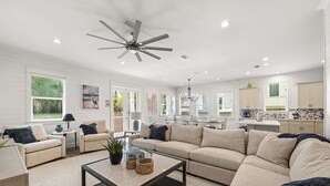 Ein geräumiges Wohnzimmer mit einem großen Ecksofa, einem Couchtisch und einem Deckenventilator.