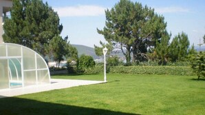 A well-maintained lawn with a white structure, possibly a gazebo, and a tall lamp post. - Langosteira Apartaments (Fisterra)
