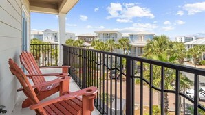 A balcony with two wooden chairs, a railing, and a view of neighboring houses.