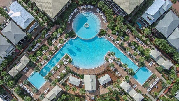 An aerial view of a hotel with multiple swimming pools, arranged in a circular pattern around a central fountain.