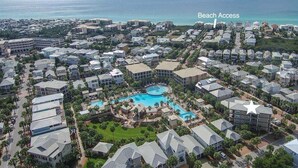 A resort with a central pool, multiple buildings, and a beach access point.