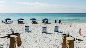A beach with sun umbrellas, lounge chairs, and a lifeguard stand.