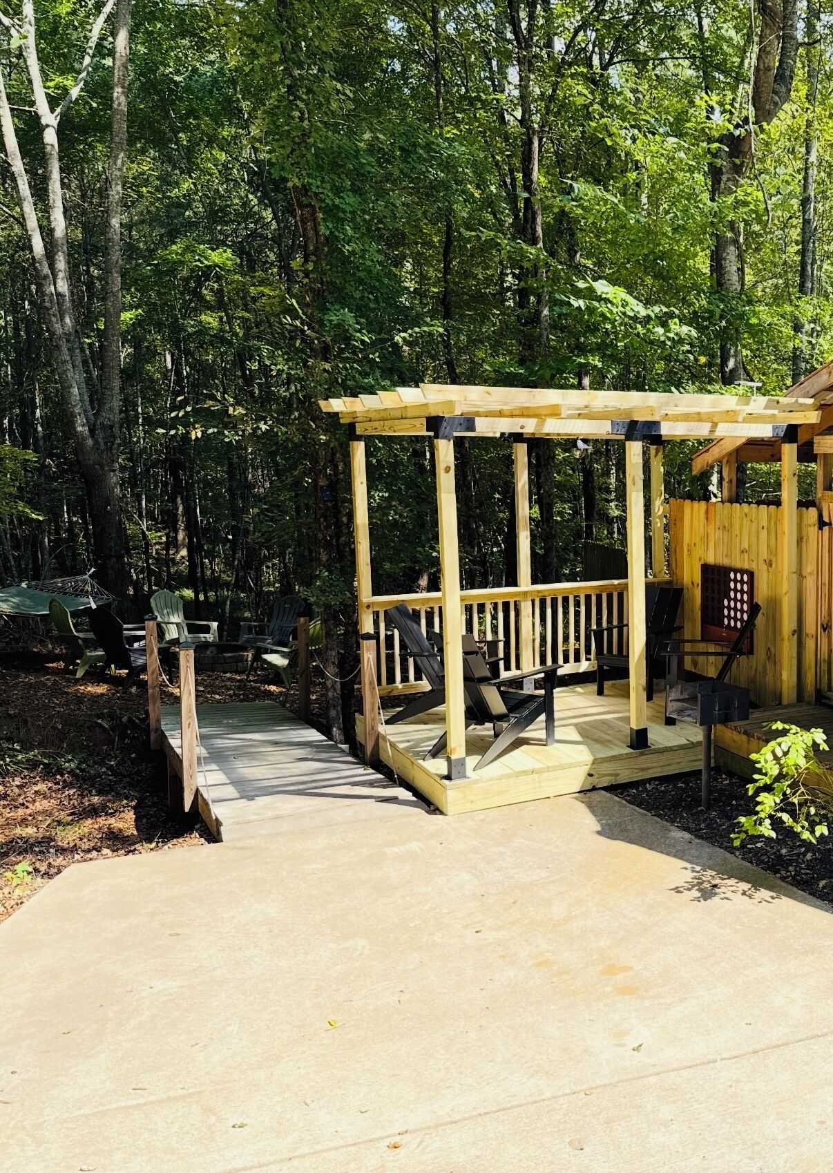 Eine Holzterrasse mit einer Pergola, umgeben von Bäumen.