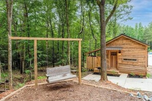 Escape to a secluded cabin nestled among tall trees, with a simple design and access to a paved pathway.