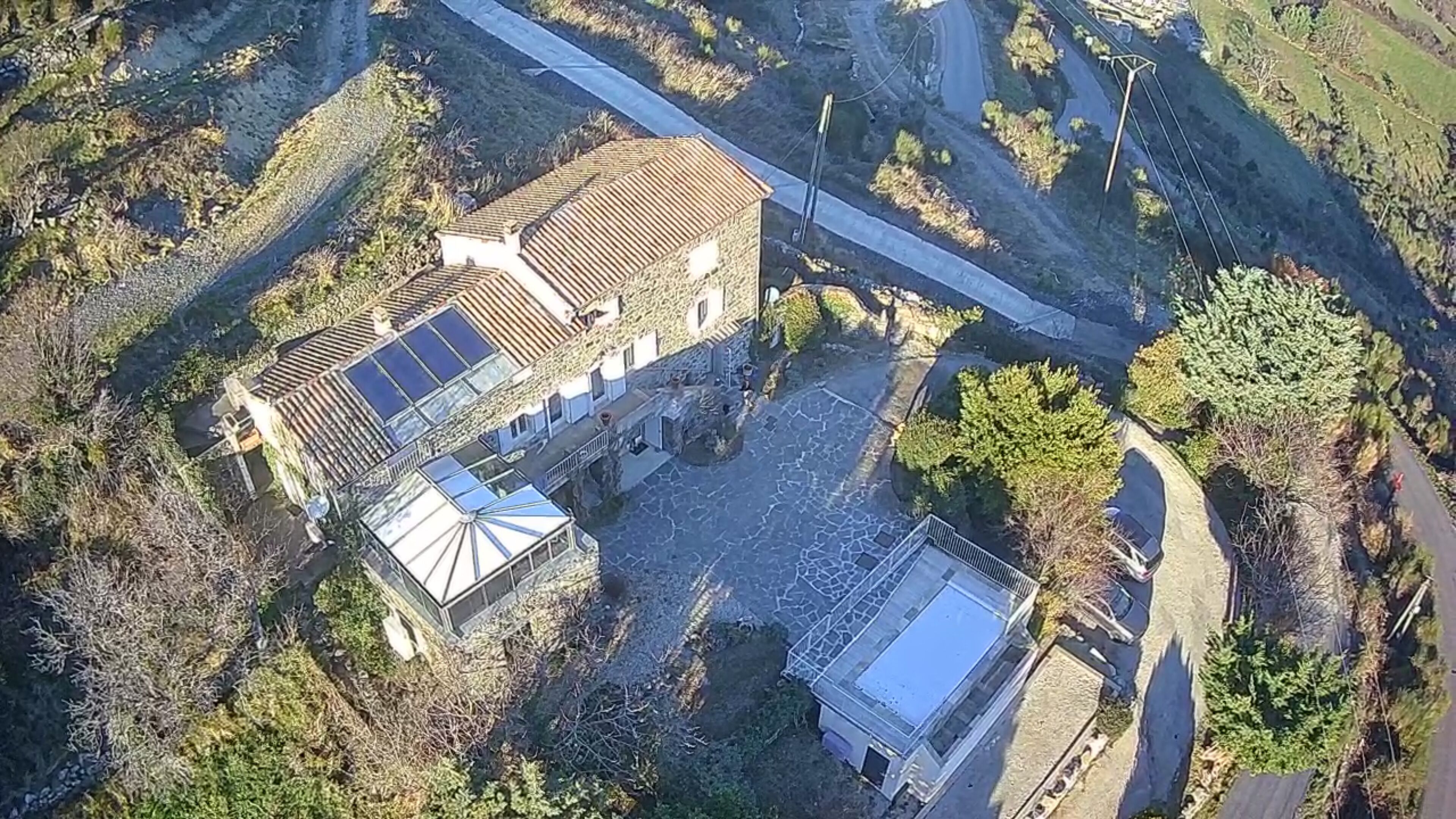 An aerial view of a building with a courtyard, a covered area with a roof, and a small adjacent structure.
