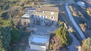 A stone building with a large terrace and a swimming pool. - Gîte in Ardèche with swimming pool and magnificent view of the valley (Rochessauve)