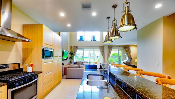 Una cocina moderna con estufa de acero inoxidable, microondas y una isla grande con pileta.
