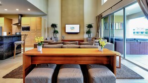 Una sala moderna con una mesa de comedor de madera, sofás grises y un televisor de pantalla plana montado en la pared.