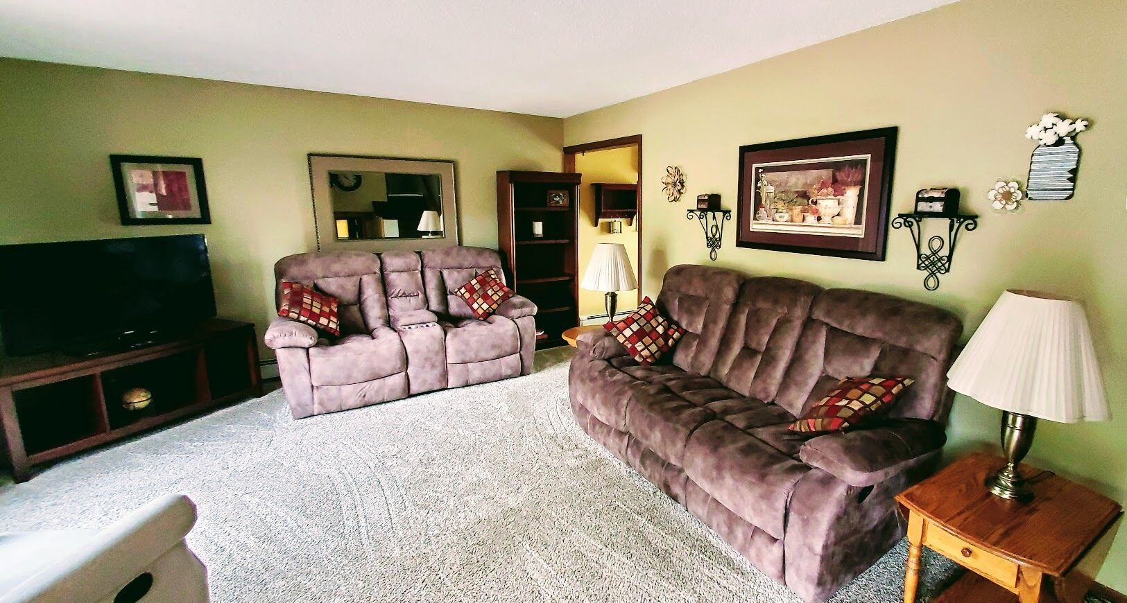 A living room with two sofas, a TV stand, a lamp, and wall decorations.