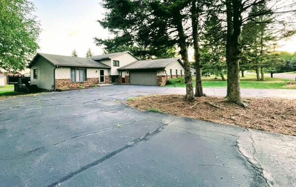 A two-story house with a garage, driveway, and surrounding trees.