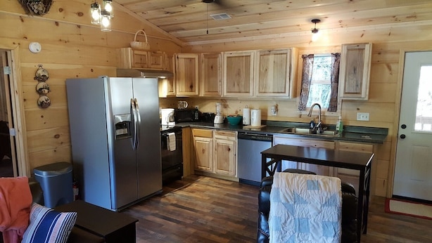 A compact kitchen with wooden cabinets, a refrigerator, a stove, and a sink.
