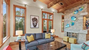 A spacious living room with a stone fireplace, large windows, and a cozy seating area. - Canyon View Retreat - Scenic & Secluded (Telluride)