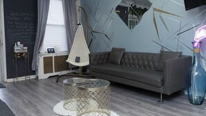 Una sala de estar moderna con un sofá gris, una silla colgante, una mesa de centro de vidrio y un letrero de neón.