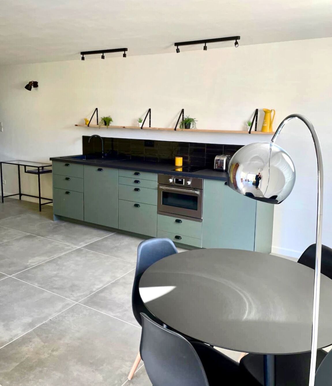 Une cuisine moderne dotée d’un îlot central, d’une table à manger avec des chaises et d’un luminaire suspendu.