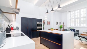 Cozinha moderna com ilha central, forno embutido e iluminação pendente.