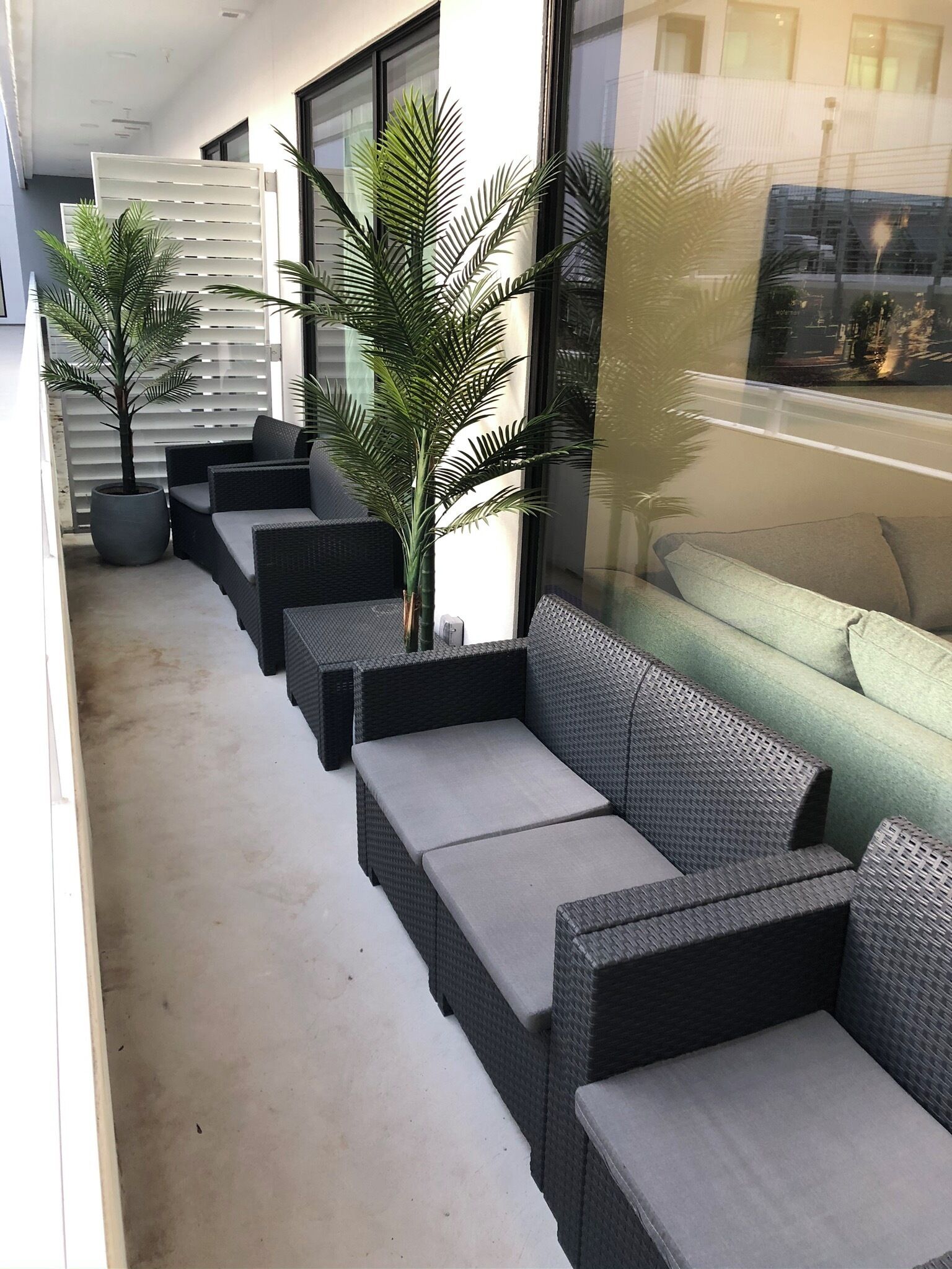 A modern outdoor seating area with wicker furniture and potted plants.