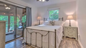 Quarto com cama, luminárias de cabeceira, janela e ventilador de teto.