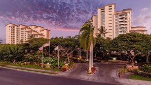 Un hotel a più piani con un cortile curato, palme e vista sulla zona circostante.
