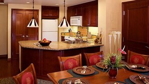 Una cucina moderna con mobili in legno scuro, un'isola centrale con lavello e illuminazione a sospensione.