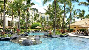 Una piscina di un resort con acqua cristallina, circondata da palme e sdraio.
