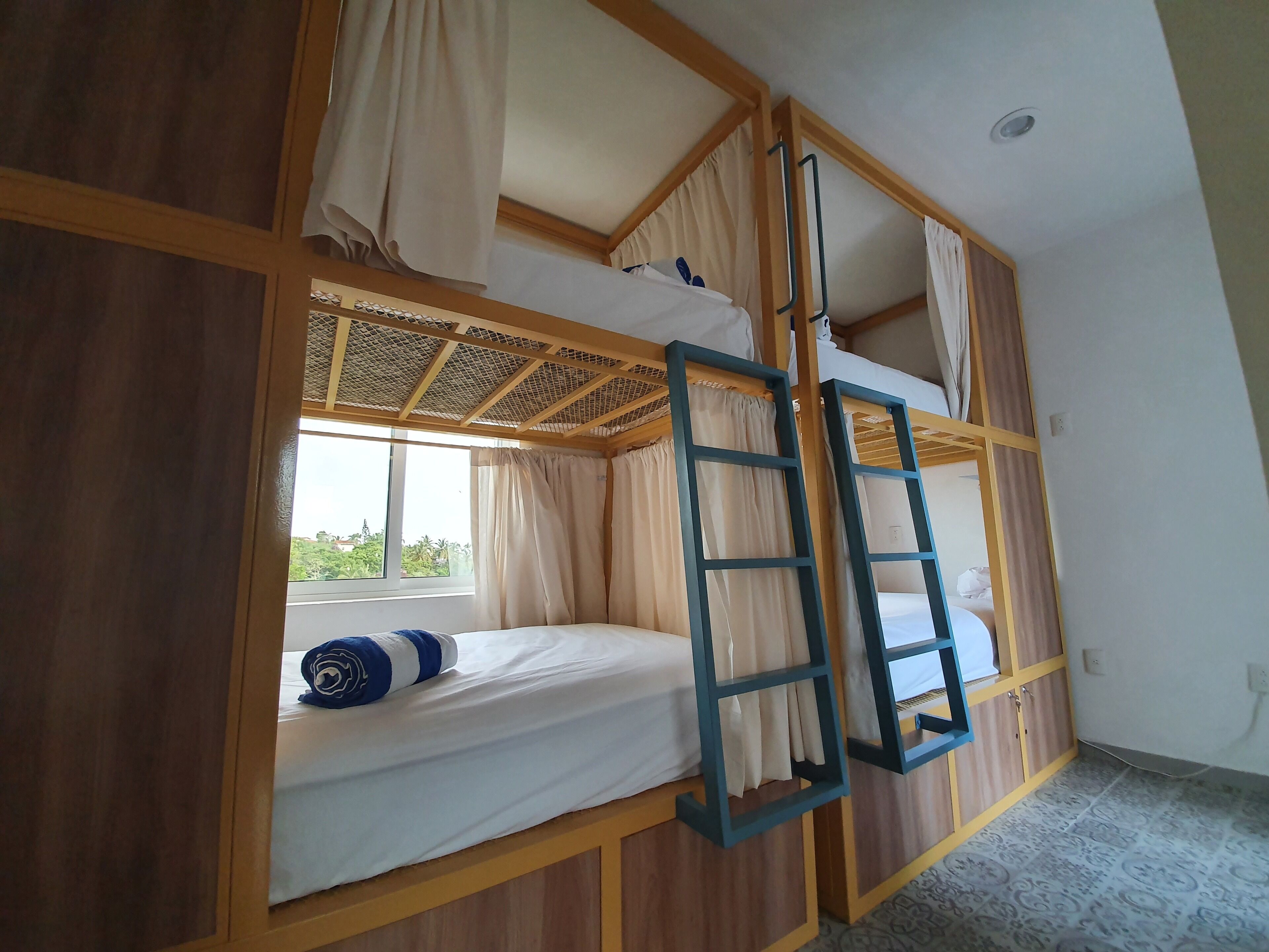 Une chambre avec un lit superposé, une échelle, un lambris en bois et une fenêtre avec des rideaux.