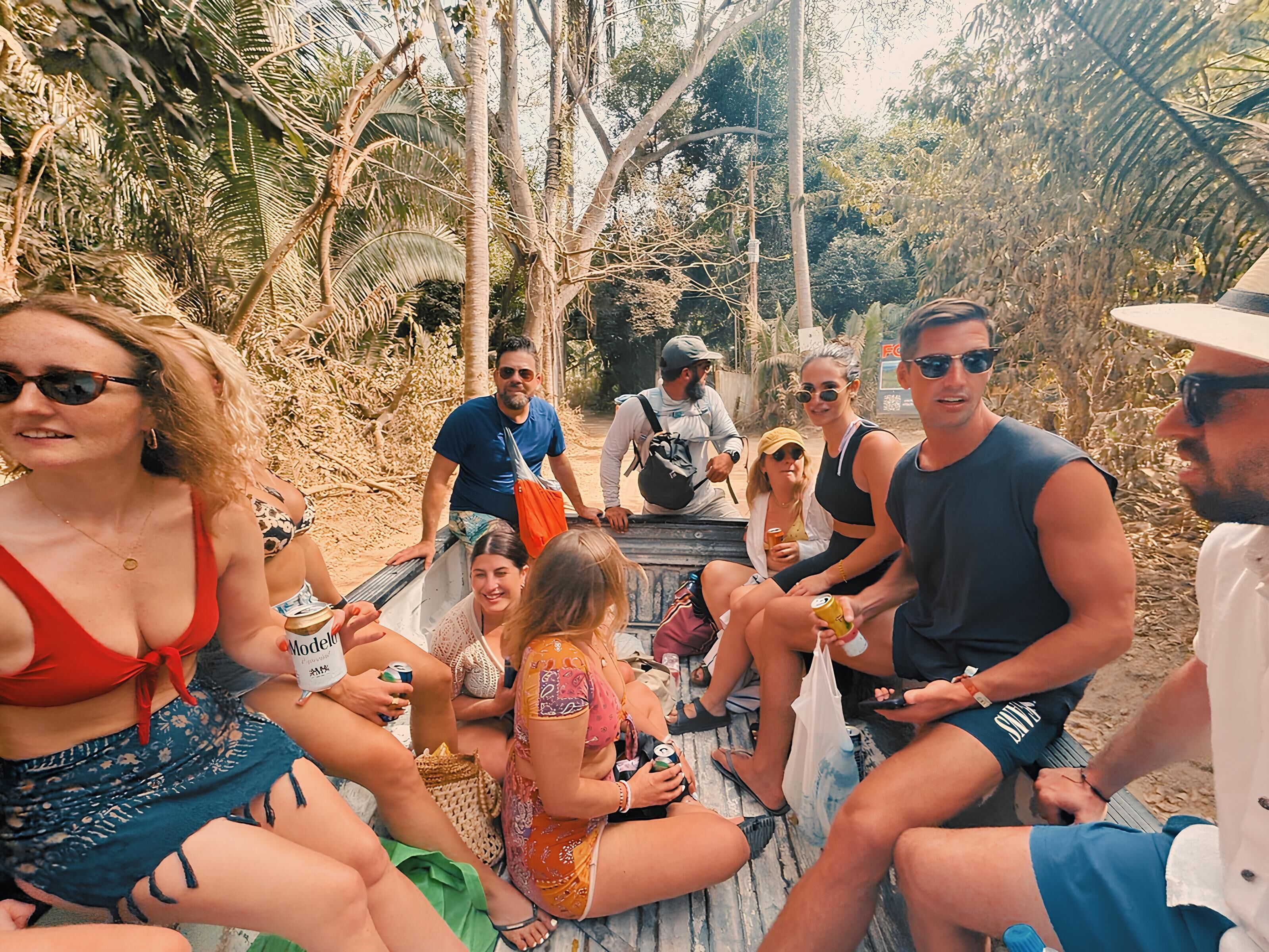 A group of people sitting on a wooden deck surrounded by dense tropical foliage.