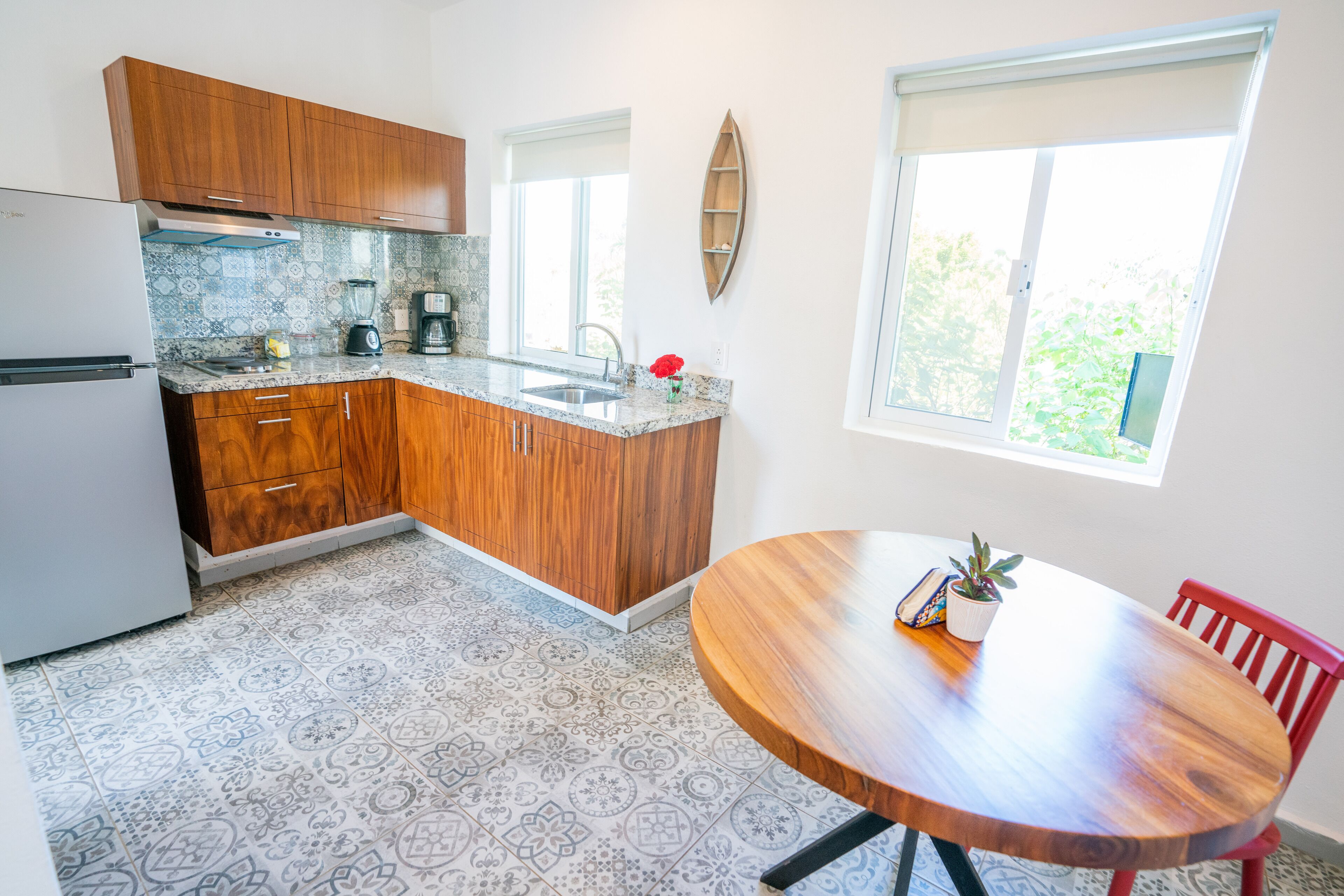 A kitchen with wooden cabinets, a white refrigerator, a sink, and a dining table with chairs.