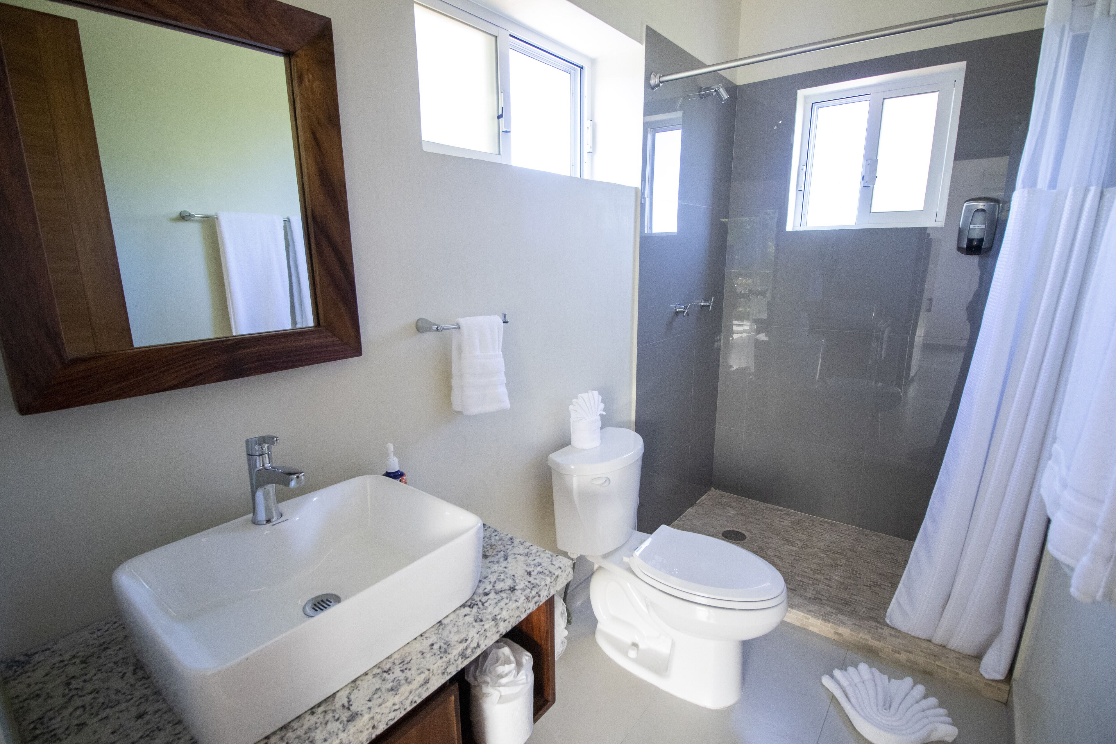 Een moderne badkamer met een groot wastafel, toilet en douche.