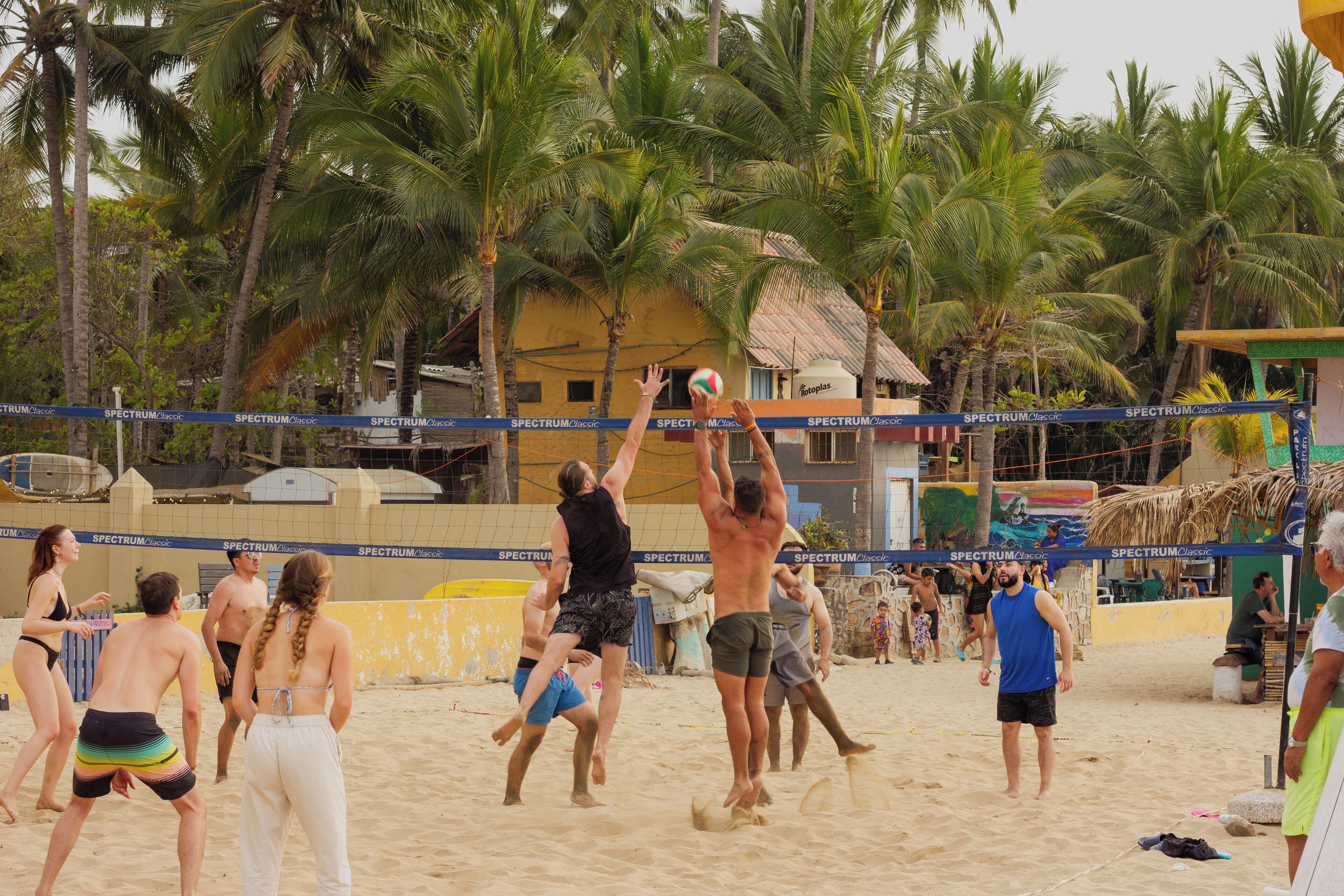 A beach volleyball game with players in various outfits.