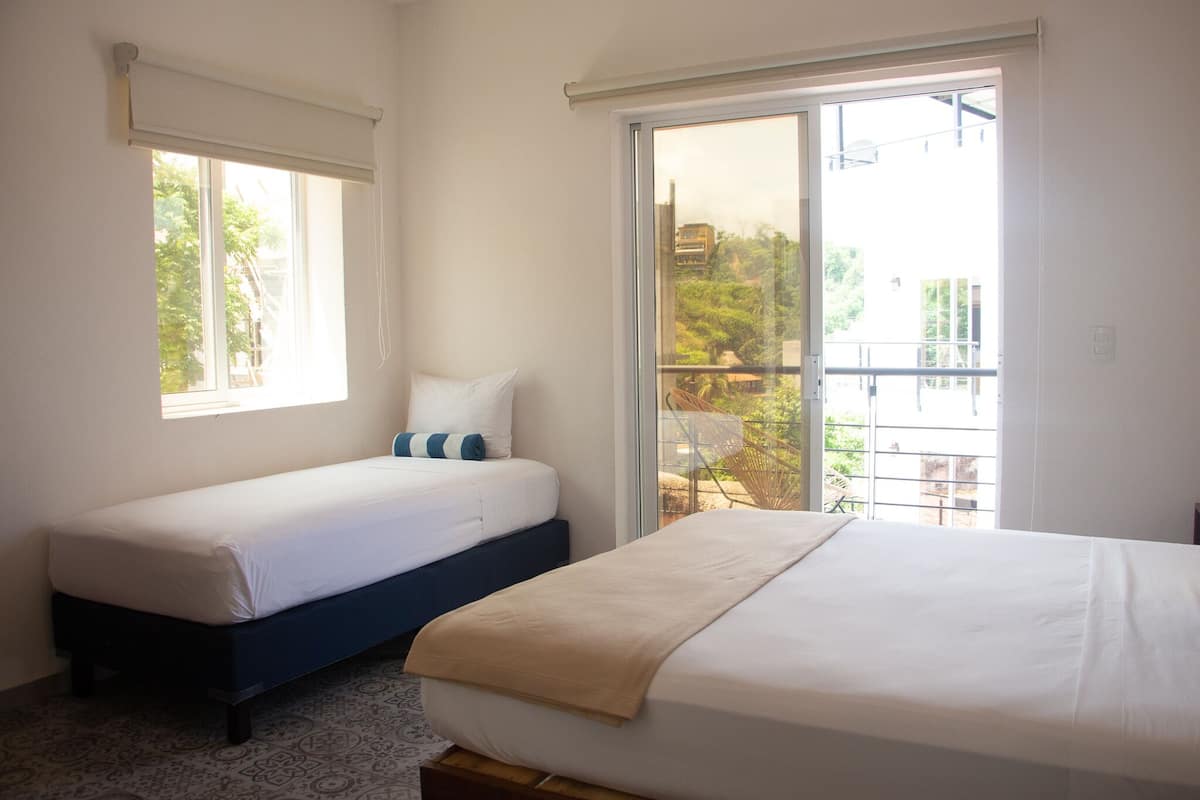 Ein Hotelzimmer mit zwei Betten, einem großen Fenster und einem Balkon.