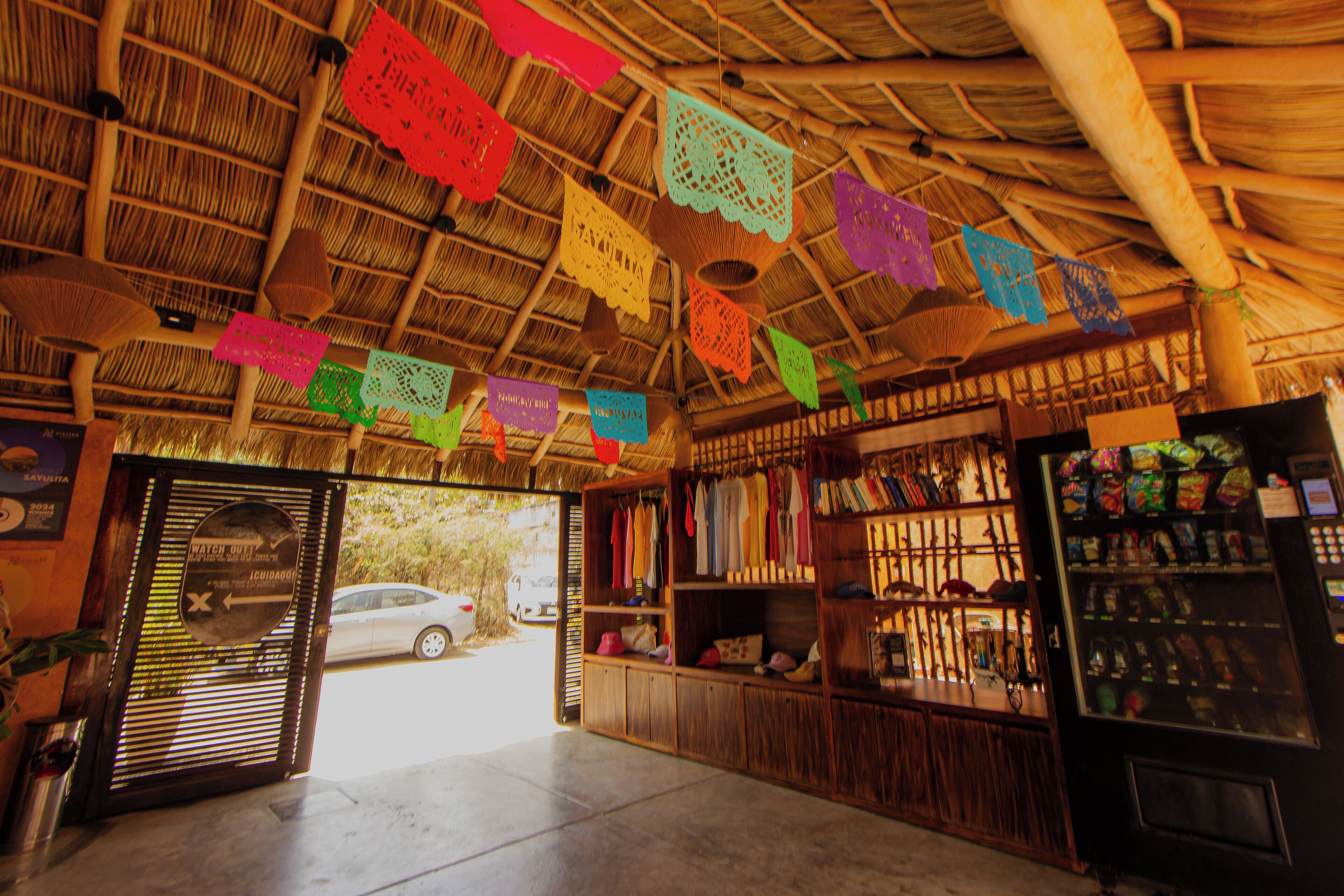 A rustic interior with a thatched roof, wooden shelves, and a vending machine.