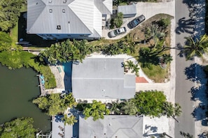 An aerial view of a property with a swimming pool, a dock, and a road with parked cars.