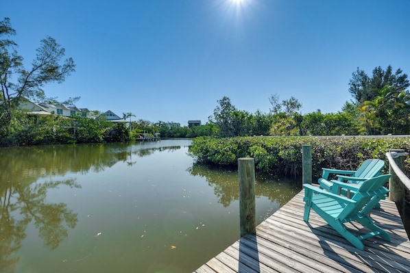A wooden dock with chairs, a calm water body, and greenery.