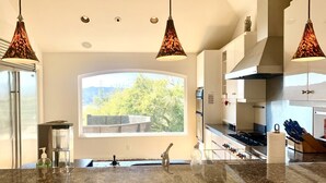 A modern kitchen with a large island, pendant lighting, and a view of the outdoors. - Take in the San Francisco views at this quiet oasis! (Tiburon)