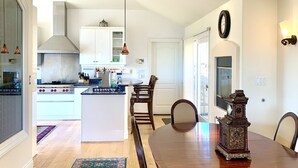 A modern kitchen with white cabinets, a central island, and a dining area with a wooden table and chairs. - Take in the San Francisco views at this quiet oasis! (Tiburon)