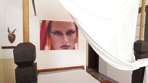 A bed with a white canopy, a wooden headboard, and a picture on the wall.