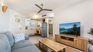 A modern living room with a grey sofa, wooden coffee table, and a TV on a wooden stand.