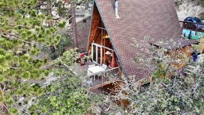 Eine Hütte mit geneigtem Dach, einem Balkon und einer kleinen Terrassenfläche.