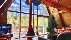 Ein gemütliches Wohnzimmer mit großem Fenster, Kamin und Fernseher.
