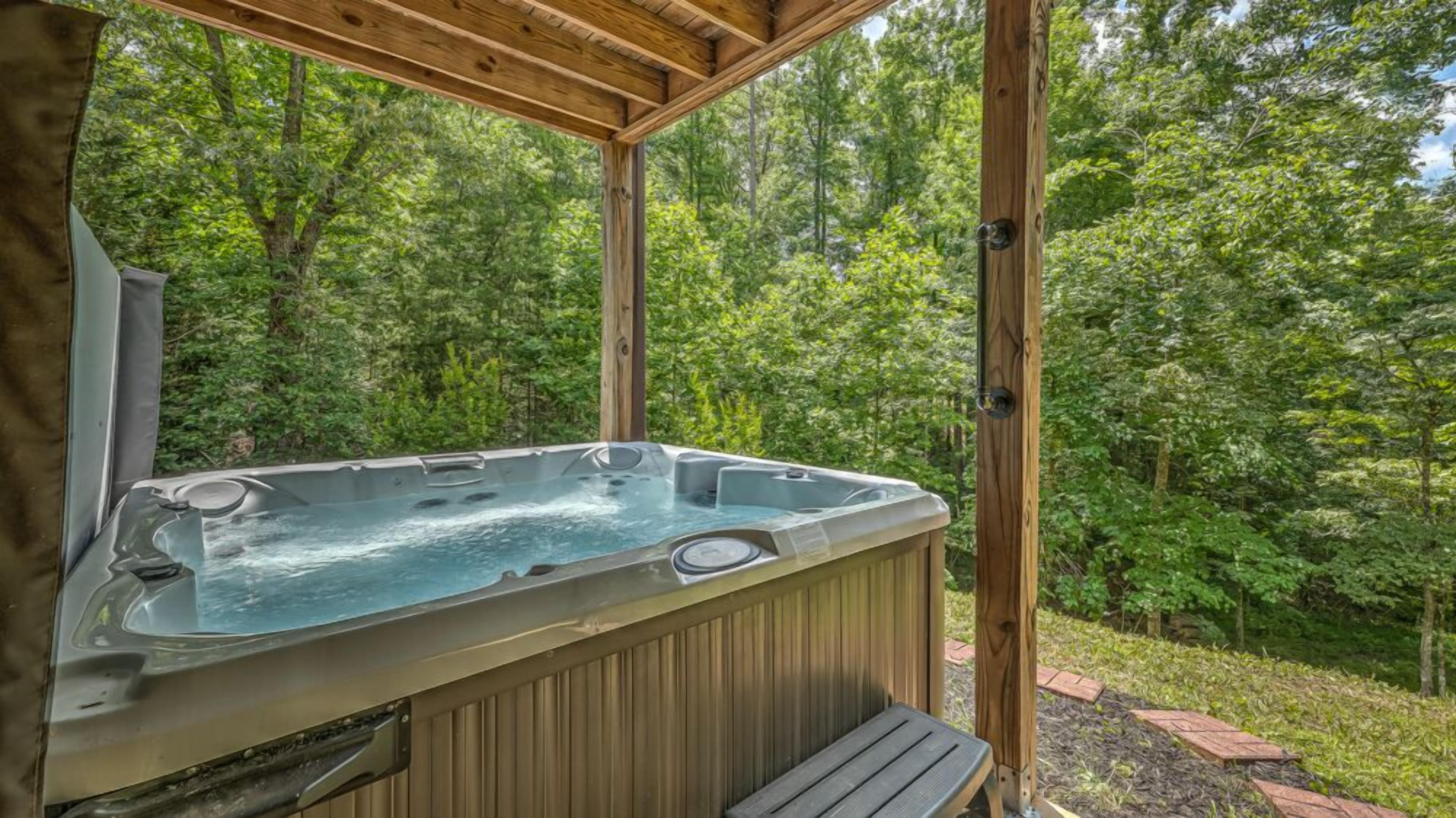 Un bain à remous installé dans un gazebo en bois, entouré d’une végétation luxuriante.
