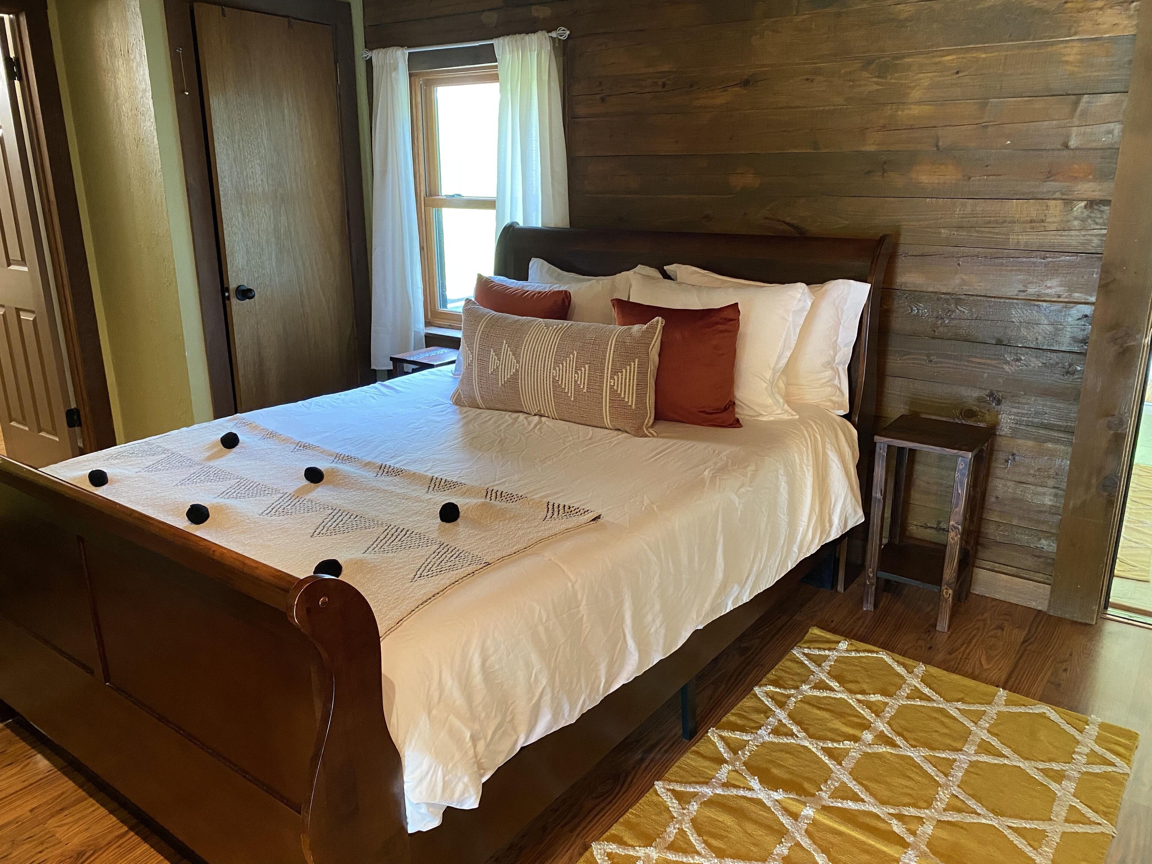 A neatly made bed with a patterned bedspread, pillows, and a small bedside table.