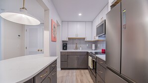 A modern kitchen with a marble countertop, stainless steel appliances, and a wooden floor. - 1 Block to Beach, heart of Old Naples, newly renovated, perfect location (Naples)