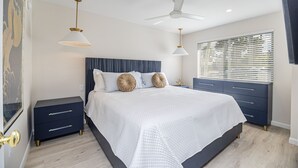 A modern bedroom with a large bed, dark nightstands, a ceiling fan, and a window with blinds. - 1 Block to Beach, heart of Old Naples, newly renovated, perfect location (Naples)