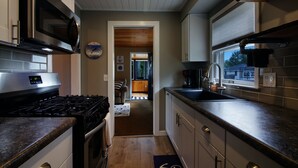 Eine moderne Küche mit Edelstahlgeräten, einer Holzbalkendecke und Blick in den Essbereich.