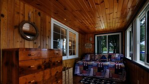 Ein Zimmer mit Holzwandverkleidung, einem Bett, einem Schminktisch und einem großen Fenster.