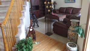 A living room with a staircase, a sofa, a coffee table, and a potted plant.