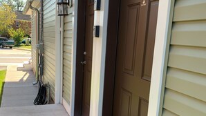 A house entrance with two brown doors, a welcome mat, and a street lamp. - 2nd floor Downtown Apartment  (Gettysburg)