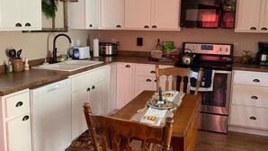 A kitchen with white cabinets, a wooden dining table, and a microwave above it. - 2nd floor Downtown Apartment  (Gettysburg)