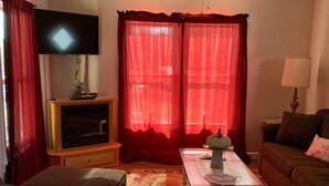 A living room with a television, a ceiling fan, a fireplace, and a sofa. - 2nd floor Downtown Apartment  (Gettysburg)